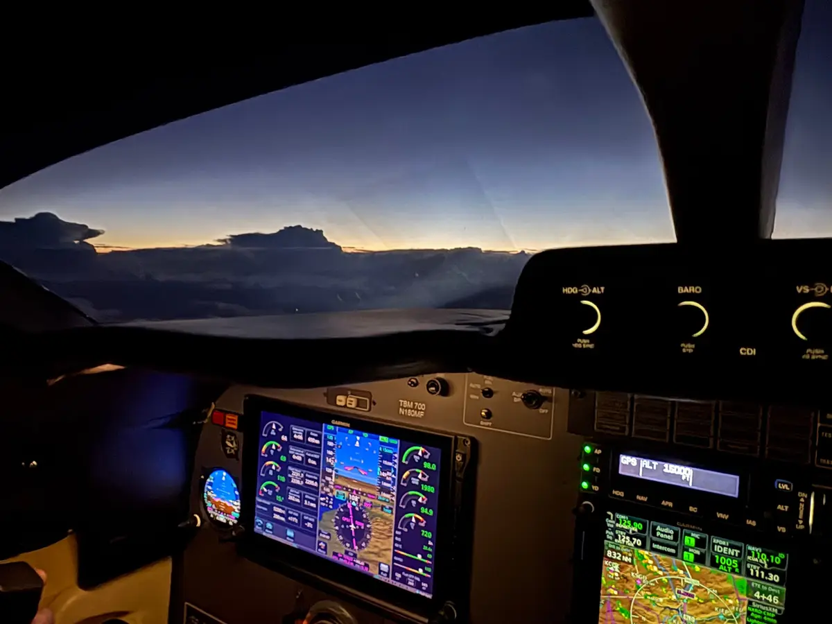 The cockpit of a TBM 700 at dusk above the clouds on the flight west to NBAA-BACE