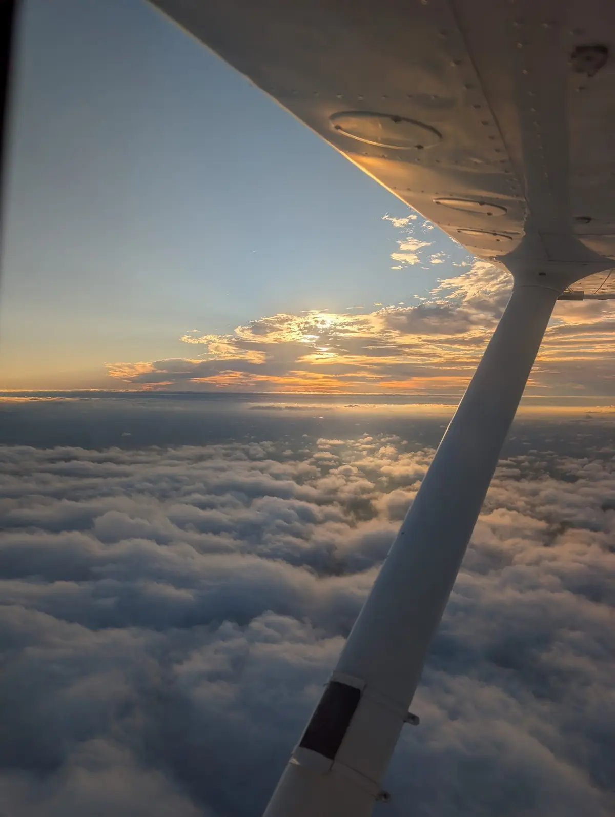 Looking out along the wing above the clouds at sunset